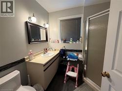 Bathroom featuring a single vanity with an integrated sink, framed mirror, and a glass-enclosed shower - 