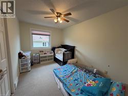 Neutral-toned room featuring a single window with a privacy blind, carpeted flooring, and a ceiling fan with integrated lighting - 