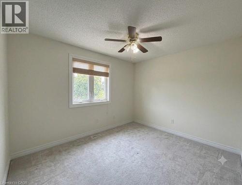 Neutral-toned room featuring light gray carpeting, a single window with blinds, and a ceiling fan with integrated lighting - 436 Gatestone Boulevard, Waterloo, ON - Indoor Photo Showing Other Room