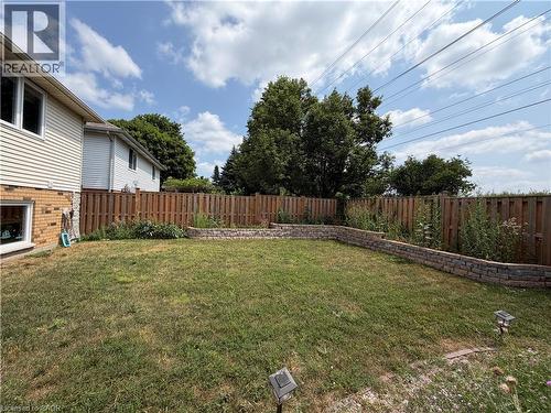Expansive backyard featuring a privacy fence, a stone retaining wall, and verdant green space - 436 Gatestone Boulevard, Waterloo, ON - Outdoor