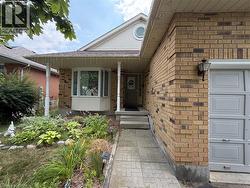 Brick exterior featuring a covered porch with white columns, a bay window, and a paneled garage door - 