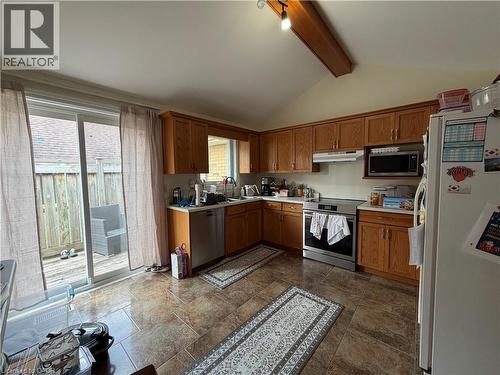 Kitchen featuring wood cabinetry, stainless steel appliances, and a vaulted ceiling with an exposed beam - 436 Gatestone Boulevard, Waterloo, ON - Indoor Photo Showing Kitchen With Double Sink
