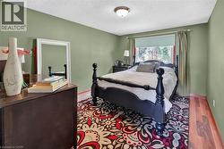 Room featuring light green walls, wood-finish flooring, a ceiling-mounted light fixture, and a window with a roller shade - 