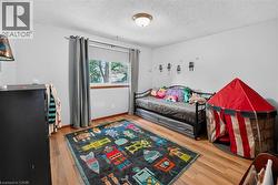 Bright room featuring wood-finish flooring and a single window with curtain rods - 