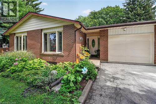 Brick exterior with a peaked roofline, an attached garage, a front entry with an oval glass insert, and a landscaped garden bed - 3 Orchard Parkway, Grimsby, ON - Outdoor With Exterior