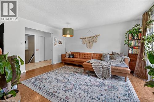 Living area featuring wood-finish flooring, a decorative area rug, and an overhead pendant light fixture - 3 Orchard Parkway, Grimsby, ON - Indoor Photo Showing Living Room