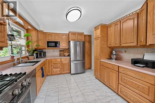 Kitchen featuring extensive wood cabinetry, L-shaped countertop space, stainless steel appliances, and tile flooring - 3 Orchard Parkway, Grimsby, ON - Indoor Photo Showing Kitchen