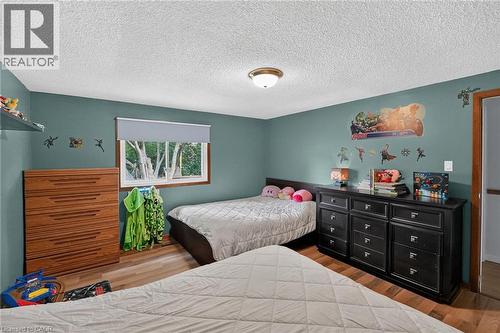 Interior room featuring wood-finish flooring, a window with a roller shade, and a flush-mount ceiling light fixture - 3 Orchard Parkway, Grimsby, ON - Indoor Photo Showing Bedroom