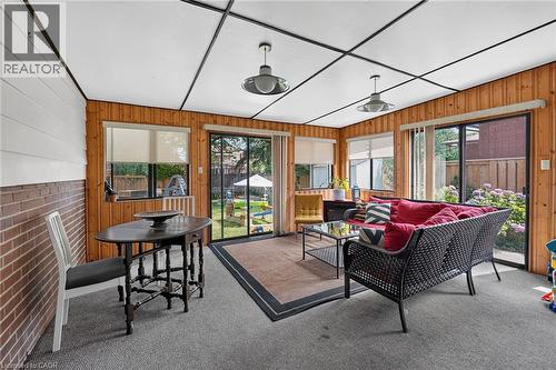 Enclosed sunroom featuring wood paneling, brick wainscoting, and large sliding glass doors providing access to the yard - 3 Orchard Parkway, Grimsby, ON - Indoor Photo Showing Other Room