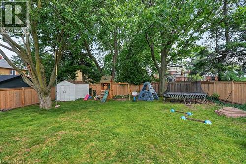 Expansive fenced backyard featuring a manicured lawn, mature trees, and a storage shed - 3 Orchard Parkway, Grimsby, ON - Outdoor With Backyard