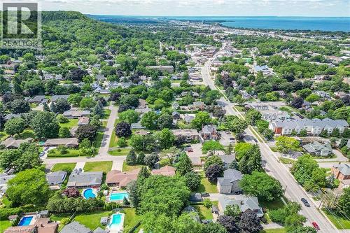 Aerial perspective showcasing a residential area with mature trees, established homes, and multiple properties featuring in-ground swimming pools - 3 Orchard Parkway, Grimsby, ON - Outdoor With View