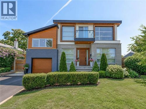 Modern architectural design featuring varied facade materials including wood-finish siding, stone, and dark brick - 5178 Hunter Drive, Burlington, ON - Outdoor With Facade