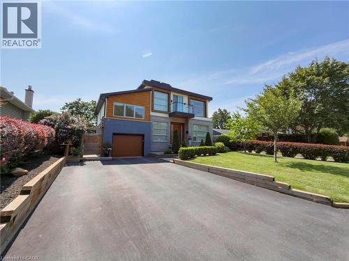 Contemporary-style residence featuring a multi-toned facade, wood-finish garage door, and a second-story balcony with glass railing - 5178 Hunter Drive, Burlington, ON - Outdoor