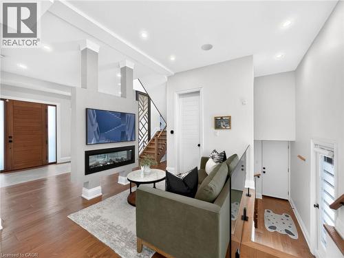 Open-concept living space featuring wood-finish flooring, recessed lighting, and a linear electric fireplace - 5178 Hunter Drive, Burlington, ON - Indoor With Fireplace
