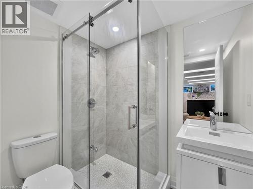 Bathroom featuring a frameless glass shower enclosure, white pebble shower floor, large format tile shower walls, and a contemporary vanity with an integrated sink - 5178 Hunter Drive, Burlington, ON - Indoor Photo Showing Bathroom
