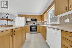 Kitchen featuring wood-finish cabinetry, tile flooring, and a tiled backsplash - 