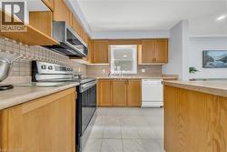 Kitchen featuring abundant wood cabinetry, light-toned countertops, tile backsplash, and stainless steel appliances including an over-the-range microwave and electric range - 