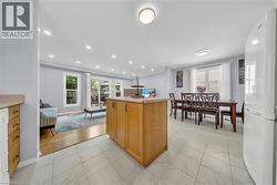 Open-concept living area featuring a central wood-finish kitchen island, light-toned tile flooring, and recessed lighting - 