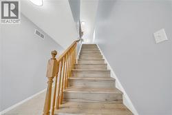Staircase featuring wood-finish treads and risers, complemented by a natural wood handrail and balusters - 