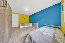 Spacious room featuring wood-finish flooring, a white paneled door, and a built-in wardrobe with vertical paneling - 
