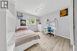 Light-toned wood-finish flooring provides a neutral base to this room, complemented by a large window with white trim - 
