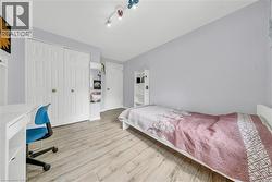 Room featuring wood-finish flooring, light grey wall paint, and a built-in closet with white bifold doors - 