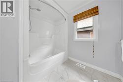 White bathtub and shower combination unit featuring a curved shower rod - 
