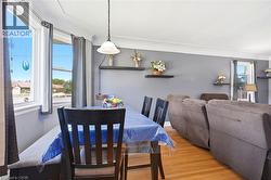 Dining area featuring wood-finish flooring, a pendant light fixture, and large windows - 