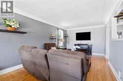 Light-filled room featuring wood-finish flooring, light gray walls, a white ceiling, and white baseboards - 