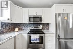 Modern kitchen featuring white shaker-style cabinetry, granite countertops, and a mosaic tile backsplash - 