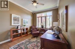 Bedroom or mainfloor office featuring wood flooring, a ceiling fan, crown molding, custom closet - 