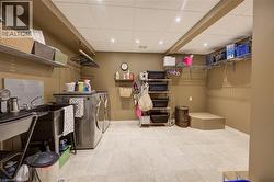 Dedicated laundry area featuring a utility sink, large capacity washer and dryer, and overhead storage shelving - 