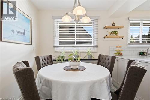 Dining area featuring a contemporary chandelier, multiple windows with blinds, a white subway tile backsplash, light-toned cabinetry, and open shelving - 11 Summit Crescent, Guelph, ON - Indoor Photo Showing Dining Room