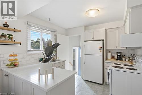 Light-filled kitchen featuring white cabinetry, subway tile backsplash, white appliances, and a solid surface countertop - 11 Summit Crescent, Guelph, ON - Indoor Photo Showing Kitchen