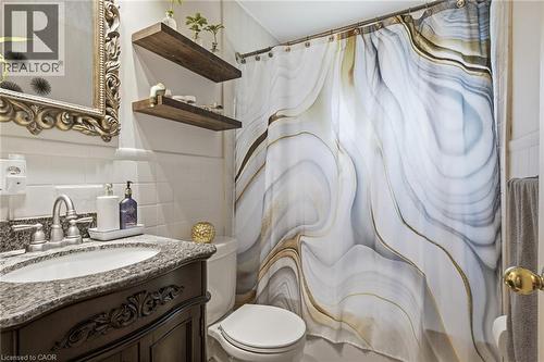Bathroom featuring a dark wood vanity with a stone countertop, an ornate framed mirror, and two floating wood shelves - 11 Summit Crescent, Guelph, ON - Indoor Photo Showing Bathroom