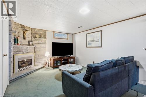 Stone-clad fireplace with a built-in gas insert, green carpet flooring, recessed ceiling light, and a horizontal window - 11 Summit Crescent, Guelph, ON - Indoor Photo Showing Living Room With Fireplace