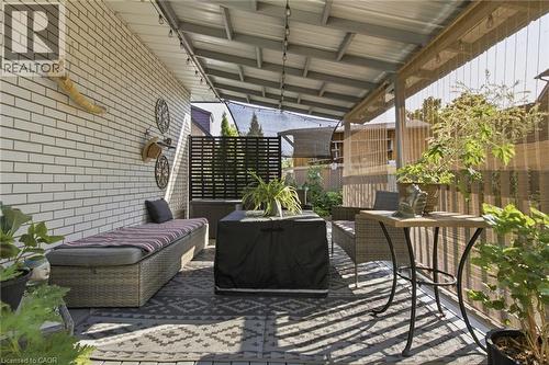 Covered patio featuring a durable metal roof, string lighting, and a white brick exterior wall - 11 Summit Crescent, Guelph, ON - Outdoor With Deck Patio Veranda With Exterior