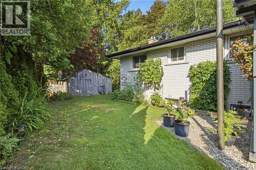 Expansive rear lawn area featuring a detached storage shed, mature perimeter landscaping, and a light-colored brick exterior - 11 Summit Crescent, Guelph, ON - Outdoor
