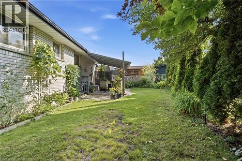 Expansive backyard featuring a manicured lawn, established privacy landscaping, and a patio area with a partial awning - 11 Summit Crescent, Guelph, ON - Outdoor