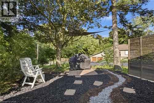 Landscaped outdoor area featuring black and grey gravel, a privacy fence, and mature trees - 11 Summit Crescent, Guelph, ON - Outdoor