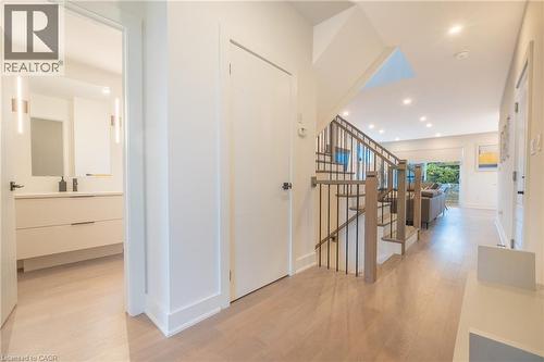 Entryway featuring light wood-finish flooring, a modern staircase with dark metal balusters, recessed lighting, and access to a bathroom with a floating vanity and vertical sconces - 9 Princeton Common, St. Catharines, ON - Indoor Photo Showing Other Room