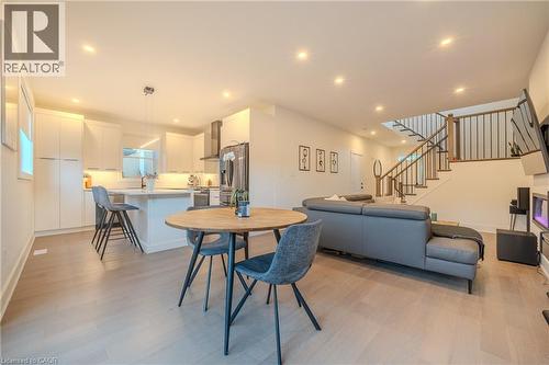 Open concept living area featuring wood-finish flooring, recessed lighting, and a contemporary staircase with dark wood handrails and black metal spindles - 9 Princeton Common, St. Catharines, ON - Indoor