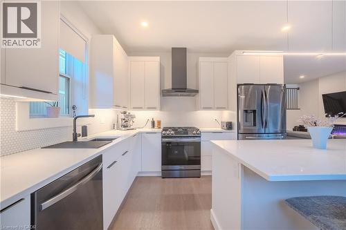 Modern kitchen featuring white flat-panel cabinetry, light-toned countertops, a stainless steel gas range with coordinating vent hood, and a deep undermount sink with a matte black faucet - 9 Princeton Common, St. Catharines, ON - Indoor Photo Showing Kitchen With Stainless Steel Kitchen With Upgraded Kitchen