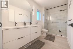 Contemporary bathroom featuring a spacious dual-sink vanity with matte black hardware, an arched frameless mirror, and modern vertical sconces - 