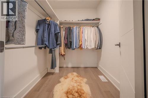 Walk-in closet featuring light wood-finish flooring, white walls, and built-in metal hanging rods - 9 Princeton Common, St. Catharines, ON - Indoor With Storage