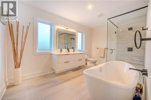 Modern bathroom featuring a freestanding soaking tub, glass-enclosed shower with tiled walls, and a double vanity with white cabinetry - 9 Princeton Common, St. Catharines, ON - Indoor Photo Showing Bathroom