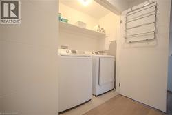 Dedicated laundry space featuring a white washer and dryer pair, recessed shelving, and tiled flooring - 