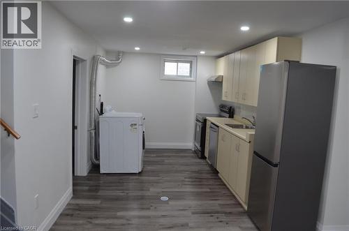 Compact kitchen area featuring wood-finish flooring, recessed lighting, and a stainless steel refrigerator - 275 Locheed Drive Unit# Lower, Hamilton, ON - Indoor Photo Showing Laundry Room