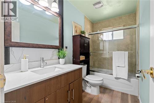 Bathroom featuring a single vanity with a white countertop and rectangular sink, wood-finish cabinetry, and a framed mirror with integrated lighting - 383 Bartley Bull Parkway, Brampton, ON - Indoor Photo Showing Bathroom