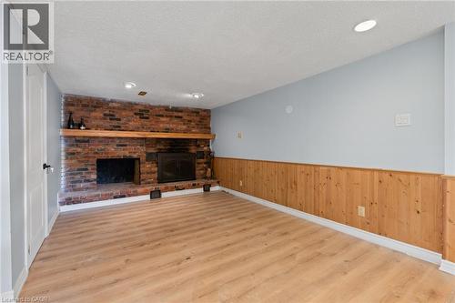 Brick fireplace with a wooden mantel, wood-finish flooring, recessed lighting, and natural wood wainscoting - 383 Bartley Bull Parkway, Brampton, ON - Indoor With Fireplace